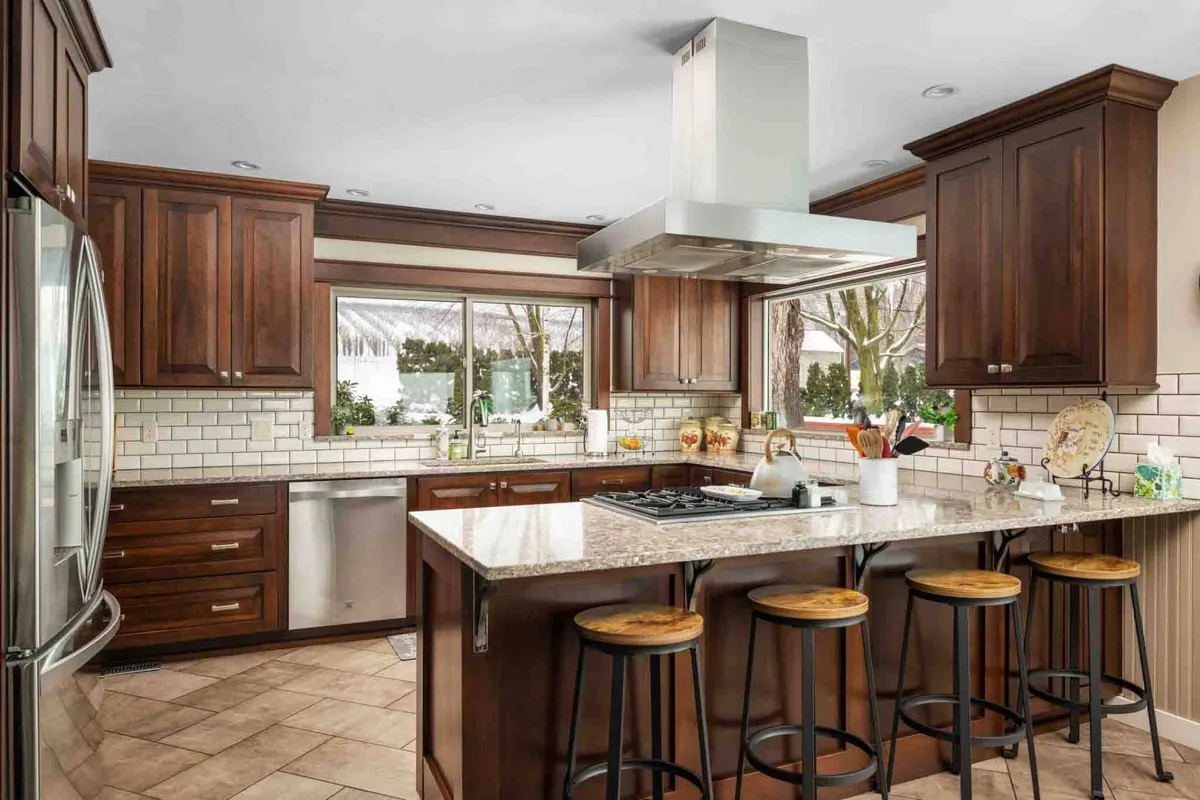A beautifully appointed chef’s kitchen featuring a granite-topped island, modern stainless steel appliances, and a sunny window view. The open, functional space is perfect for preparing family meals or entertaining, blending modern convenience with timeless character.
