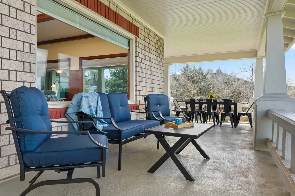 An inviting deck scene featuring blue chairs, a dining table, and a coffee table—all set against the backdrop of a lush landscape. The arrangement is perfect for relaxing, enjoying coffee or tea, and gathering with friends or family while taking in the panoramic views.