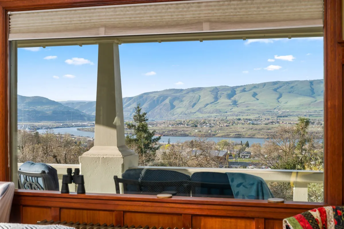 A sweeping view of the mountain range, river, trees, and outdoor seating, capturing the sense of tranquility and openness. The image evokes possibilities for stargazing, wildlife observation, and small outdoor gatherings in a serene, natural setting.
